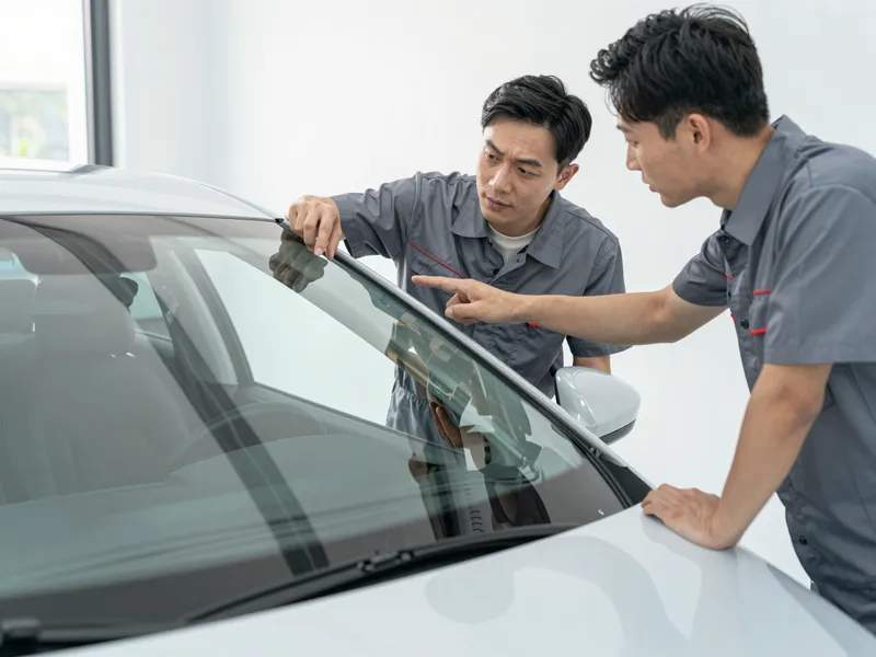 Ein Autoglas-Berater erklaert einem Kunden die Reparatur an einer Autoscheibe