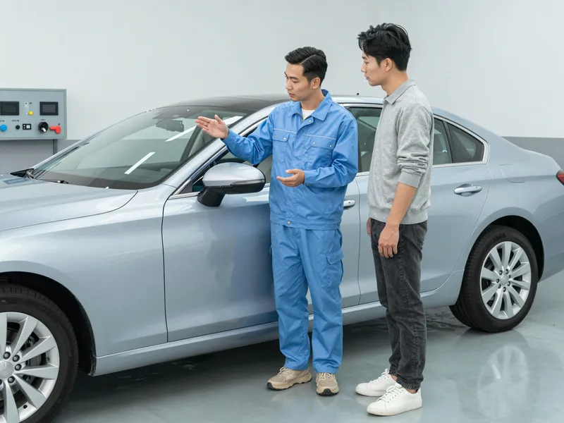 Ein Automechaniker erklärt einem Kunden den Glasreparaturprozess in einer sauberen Werkstatt.