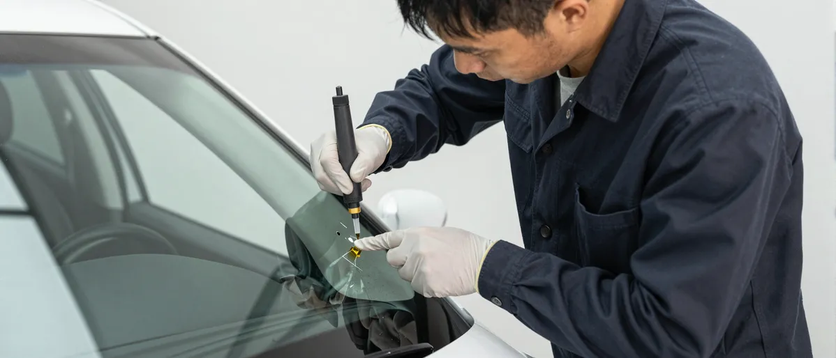 Werkzeuge und Materialien fuer die Autoglasreparatur liegen auf einer Werkbank