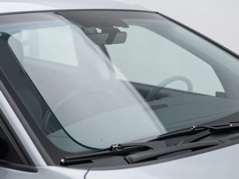 Ein makellos neues Autofrontglas, klar und ohne Kratzer, mit sauberem Armaturenbrett und Lenkrad im Hintergrund.