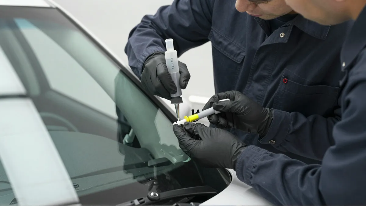 Werkzeuge und Materialien fuer die Autoglasreparatur liegen auf einer Werkbank